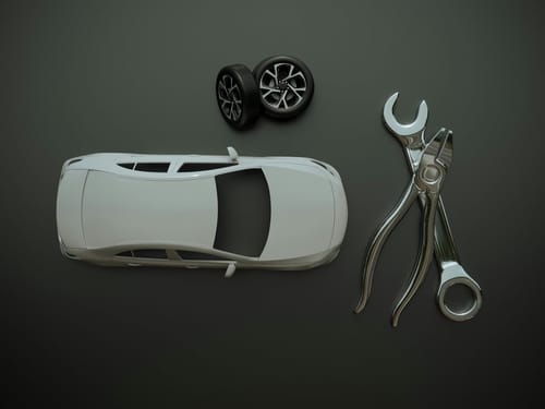 A clean overhead view of a 3D model of a white car with a pair of wheels, a large spanner and pliers, on a dark grey background. The pieces illustrate custom production of automotive parts and prototypes by 3D printing.