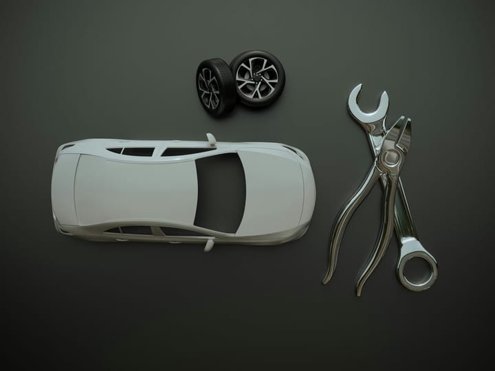 A clean overhead view of a 3D model of a white car with a pair of wheels, a large spanner and pliers, on a dark grey background. The pieces illustrate custom production of automotive parts and prototypes by 3D printing.