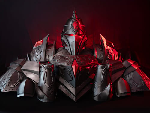 A complete, detailed set of cosplay armour, 3D printed in a metallic finish and lit in red. It shows the helmet, shoulder and chest plates with ornamental engraving and spiked elements, illustrating the use of 3D printing for complex film props and cosplay costume.