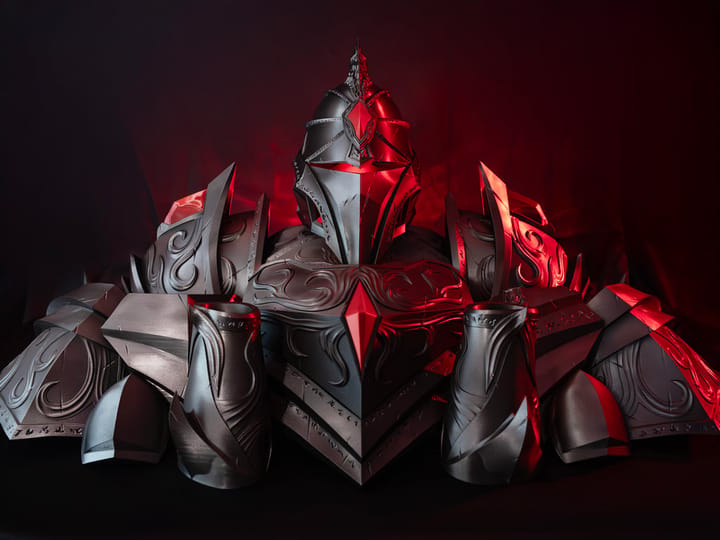 A complete, detailed set of cosplay armour, 3D printed in a metallic finish and lit in red. It shows the helmet, shoulder and chest plates with ornamental engraving and spiked elements, illustrating the use of 3D printing for complex film props and cosplay costume.