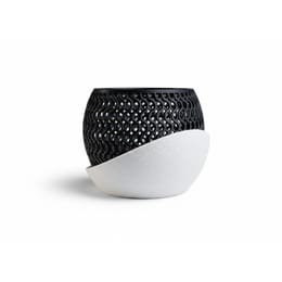 A black, intricately patterned orchid pot sits on a white, textured base against a white background.