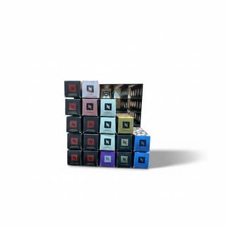 Plný stojan na Nespresso kapsle s mnoha barevnými krabičkami z předního pohledu.